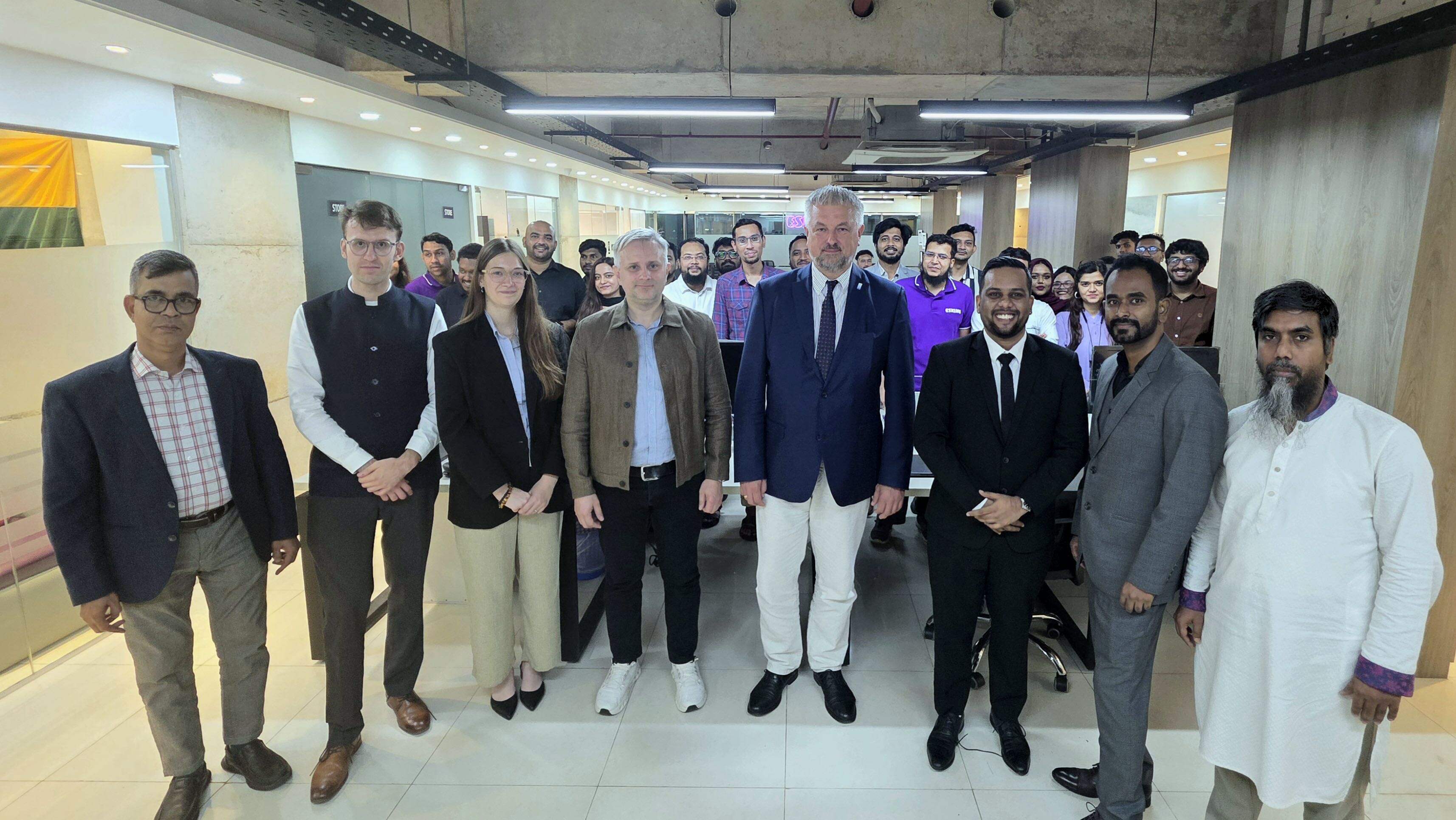 Lithuania's Vice-Minister of Foreign Affairs and members of the delegation standing with the Eskimi team in the Bangladesh office.